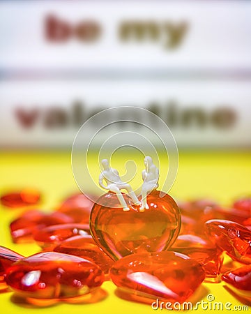 Miniature couple sitting on Red glass hearts, Valentineâ€™s Day concept Stock Photo